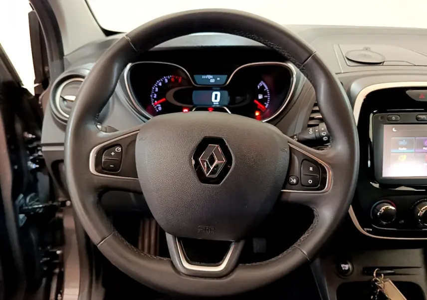 Intérieur du Renault Captur Business gris foncé, vue centrée sur le volant cuir multifonctions et le tableau de bord numérique.