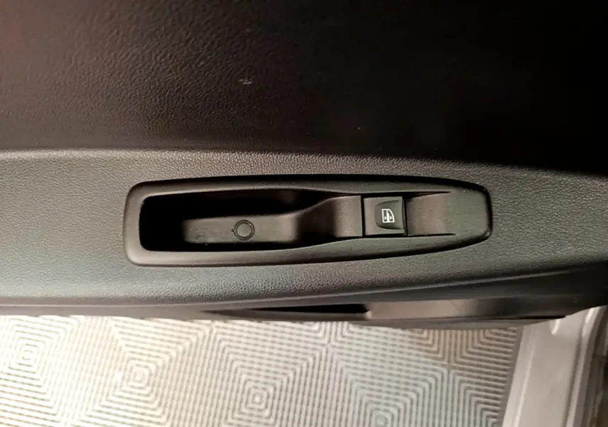 Bouton de commande électrique de la vitre sur la portière intérieure d'un Renault Captur gris foncé, vue rapprochée.