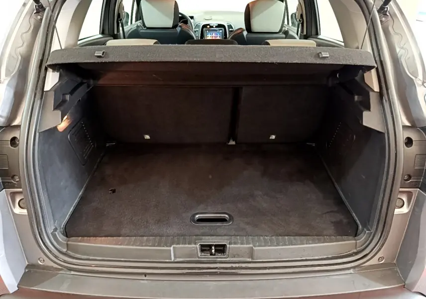 Coffre ouvert vu de l'arrière d'un Renault Captur gris foncé, montrant l'espace de chargement et les sièges arrière.