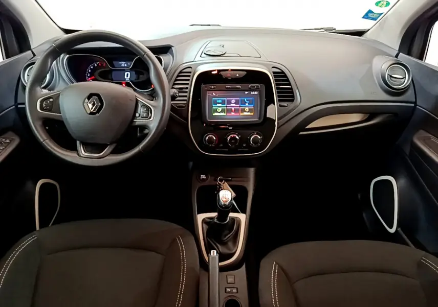Vue intérieure frontale du tableau de bord du Renault Captur Business gris foncé avec écran tactile et volant cuir multifonctions.