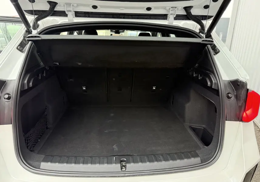 Coffre ouvert vu de l'arrière d'un BMW X1 blanc minéral, montrant un espace de chargement propre et spacieux.