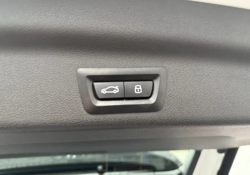 Boutons de fermeture et verrouillage électrique du hayon sur la partie intérieure du coffre d'un BMW X1 blanc minéral 2025.