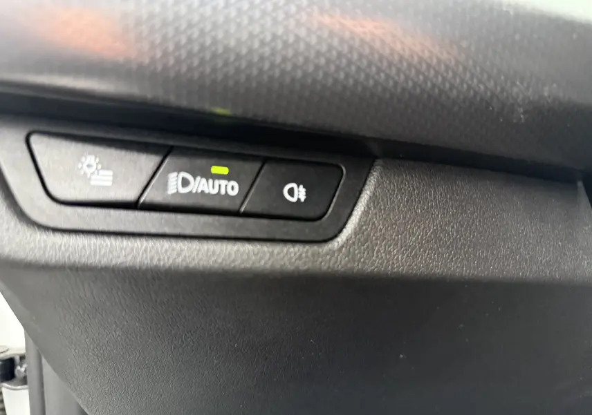 Boutons de commande des phares avec fonction auto activée sur le tableau de bord d'un BMW X1 blanc mineral 2025.