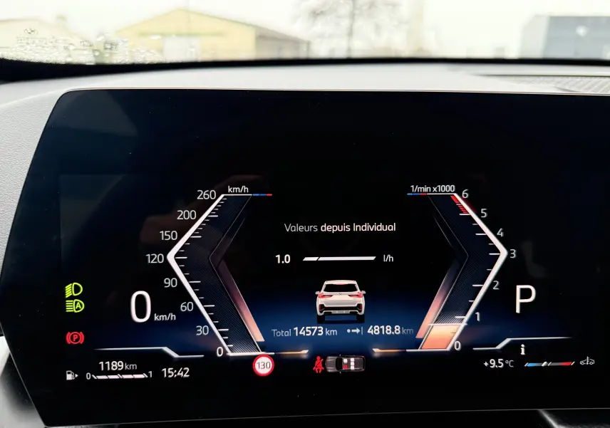 Tableau de bord numérique du BMW X1 blanc mineral 2025 affichant la vitesse, régime moteur et indicateurs de conduite.