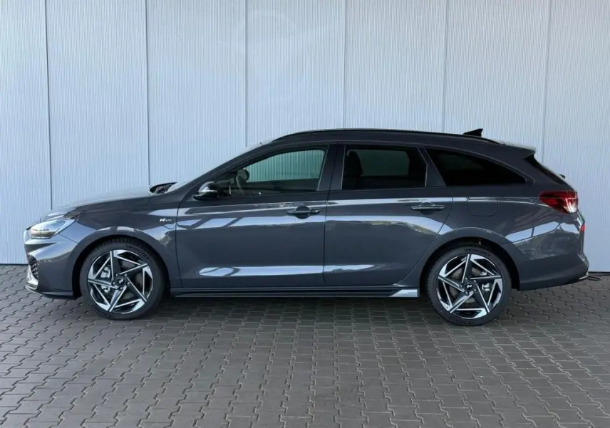 Vue de profil côté gauche d'une Hyundai i30 SW N-LINE gris foncé avec jantes alliage sport et vitres teintées.
