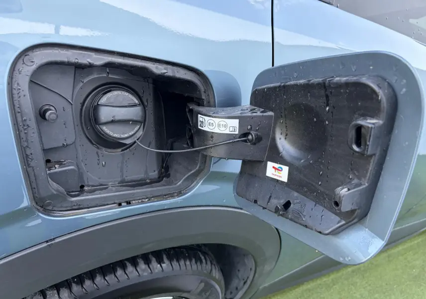 Gros plan sur la trappe à carburant ouverte côté gauche d’un Peugeot 3008 bleu Ingaro avec bouchon essence visible.