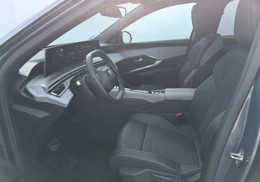 Intérieur avant droit du Peugeot 3008 bleu Ingaro 2024, avec tableau de bord i-Cockpit panoramique et sellerie tissu gris et noir.
