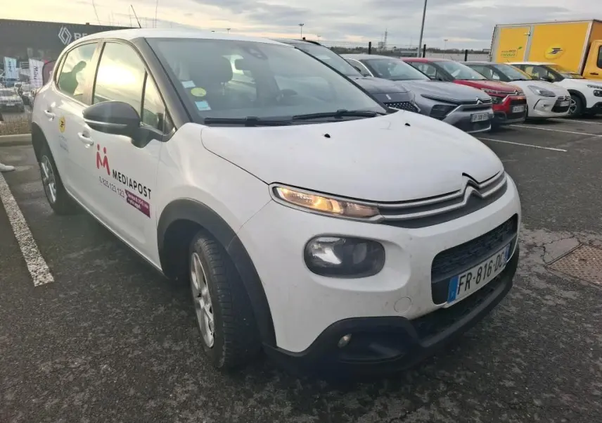 Vue 3/4 avant gauche d'une Citroën C3 Société blanche avec logo Mediapost sur la porte, stationnée sur un parking.