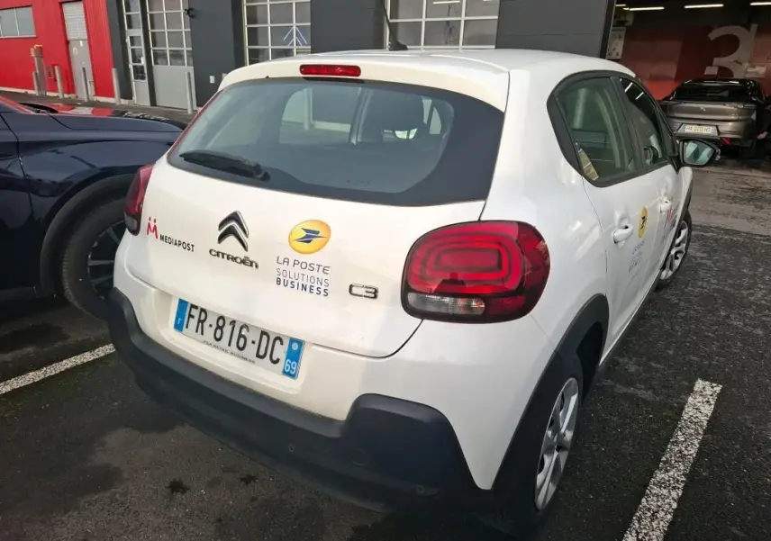 Vue 3/4 arrière droite d'une Citroën C3 blanche 2020 avec logos La Poste et Mediapost sur parking.