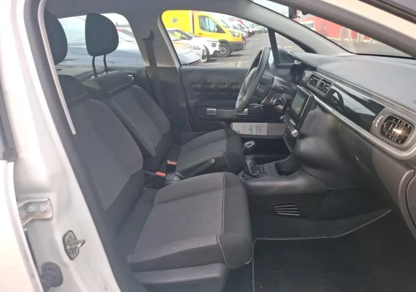 Vue intérieure côté gauche de la Citroën C3 Société blanche, montrant les sièges avant et le tableau de bord avec écran tactile.