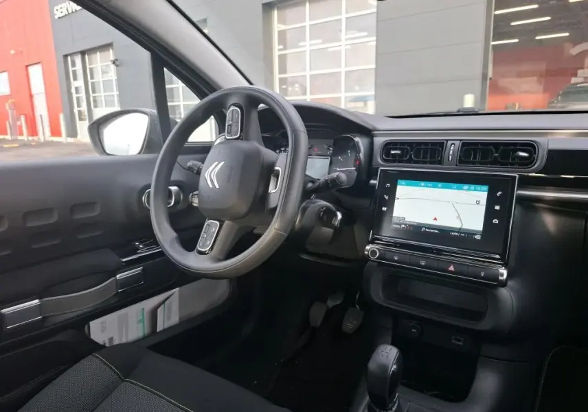 Vue intérieure côté conducteur de la Citroën C3 Société 2020, tableau de bord noir avec écran tactile et volant multifonction.