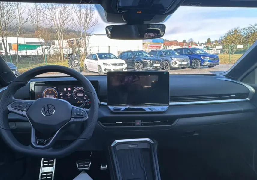 Vue intérieure frontale du tableau de bord noir du Volkswagen T-Roc 2026 avec volant multifonctions et écran tactile central.