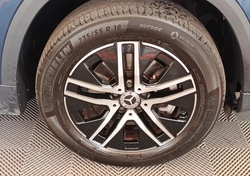 Gros plan sur la roue avant droite avec jante alliage noir et argentée d'une Mercedes GLA 250 e gris foncé.