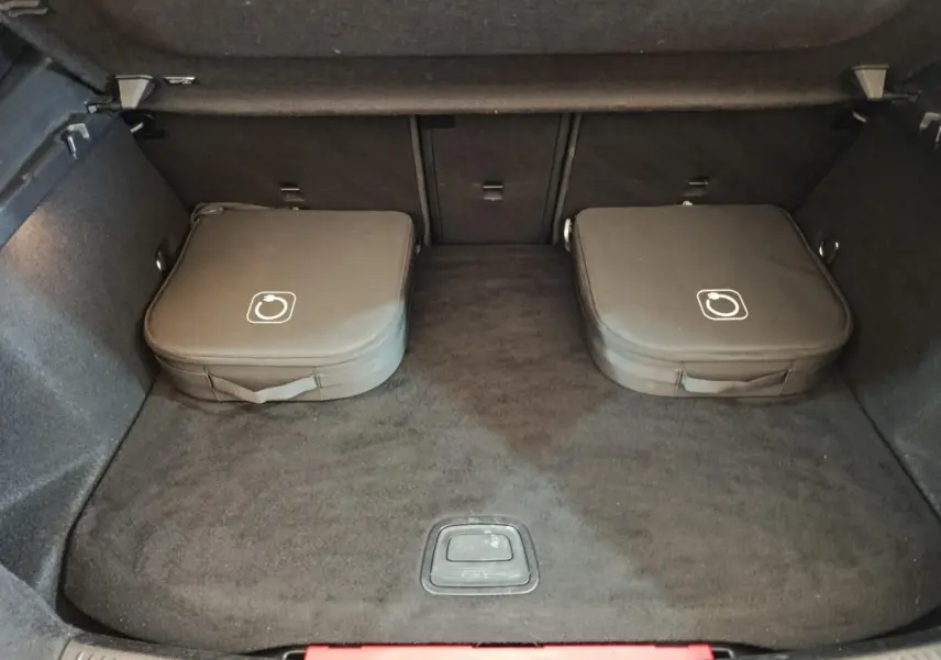 Coffre spacieux d’un Mercedes GLA 250 e Business Line gris foncé, avec deux sacs de rangement noirs posés à plat.