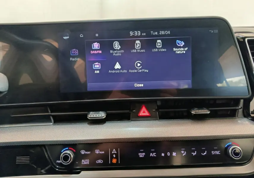 Vue rapprochée de l’écran tactile central du tableau de bord du Kia Sportage blanc, affichant les options multimédias.
