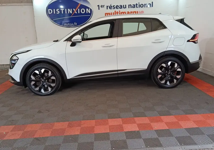 Vue de profil côté gauche d'un KIA SPORTAGE blanc hybride rechargeable avec jantes noires et détails noirs contrastants.