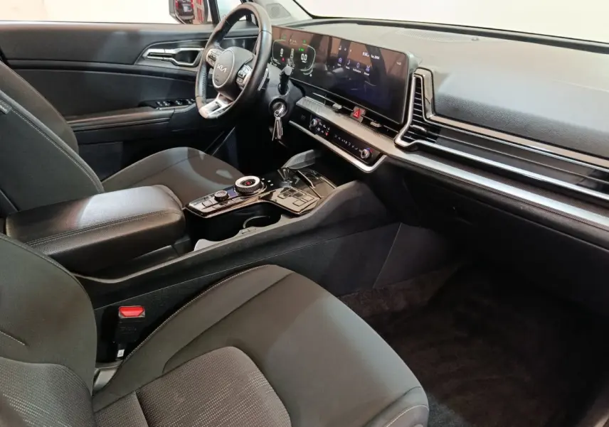 Vue intérieure côté conducteur du tableau de bord et console centrale du KIA SPORTAGE hybride rechargeable 2022, finition noire.