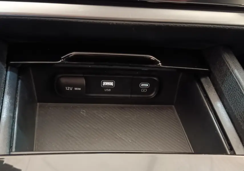 Gros plan sur la console centrale noire du Kia Sportage 2022 avec prises USB et 12V visibles.