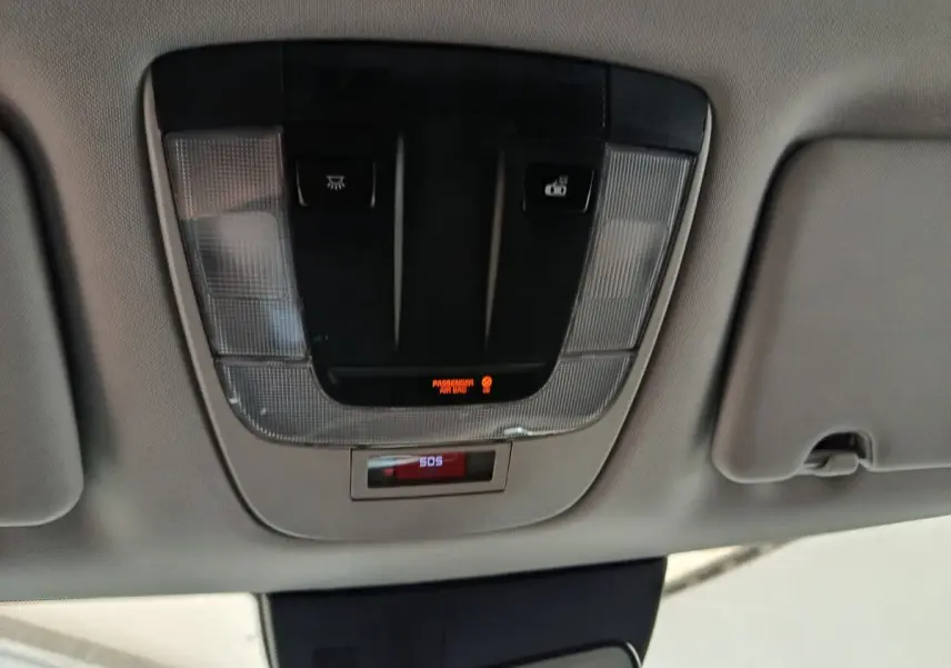Vue en gros plan du plafonnier gris avec boutons d'éclairage et alerte SOS dans un Kia Sportage blanc 2022.