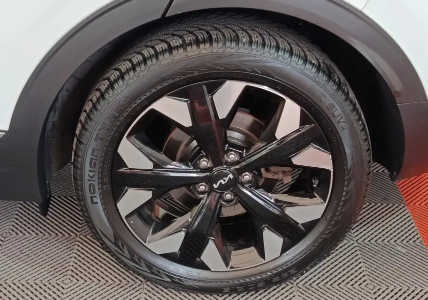 Gros plan sur la roue avant droite du KIA Sportage blanc, mettant en valeur la jante noire et argentée au design moderne.