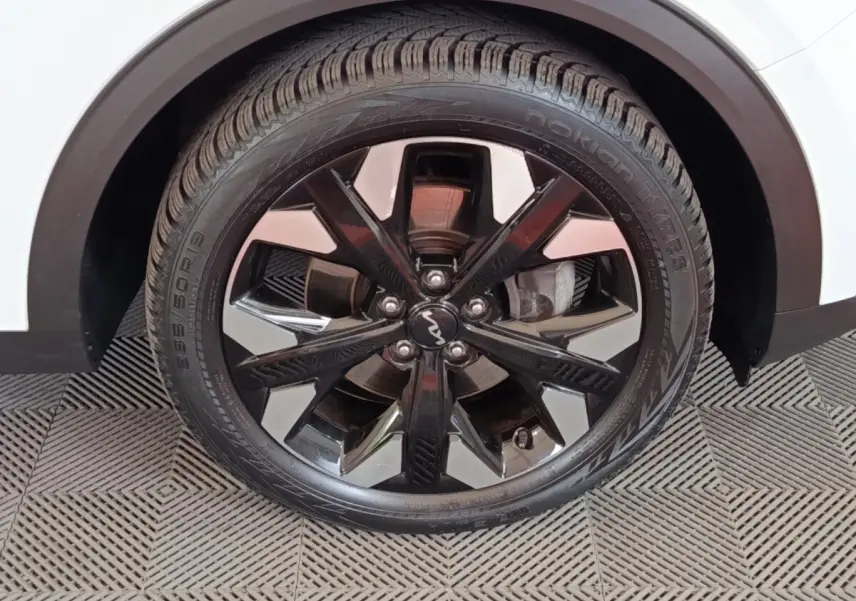 Gros plan sur la roue arrière droite noire et chromée du KIA SPORTAGE blanc 2022, jante alliage distinctive.