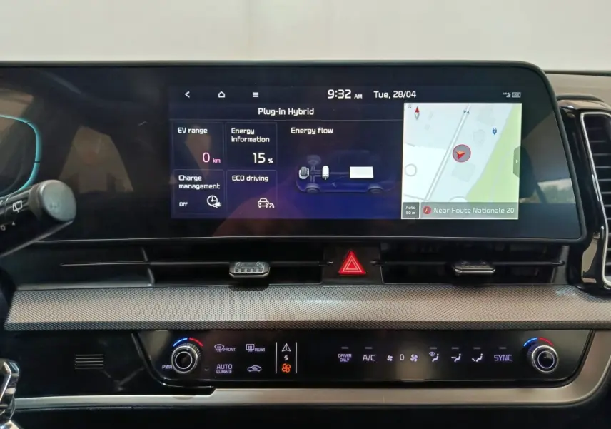 Vue rapprochée du tableau de bord numérique du Kia Sportage hybride rechargeable 2022 avec écran tactile affichant navigation et données énergie.