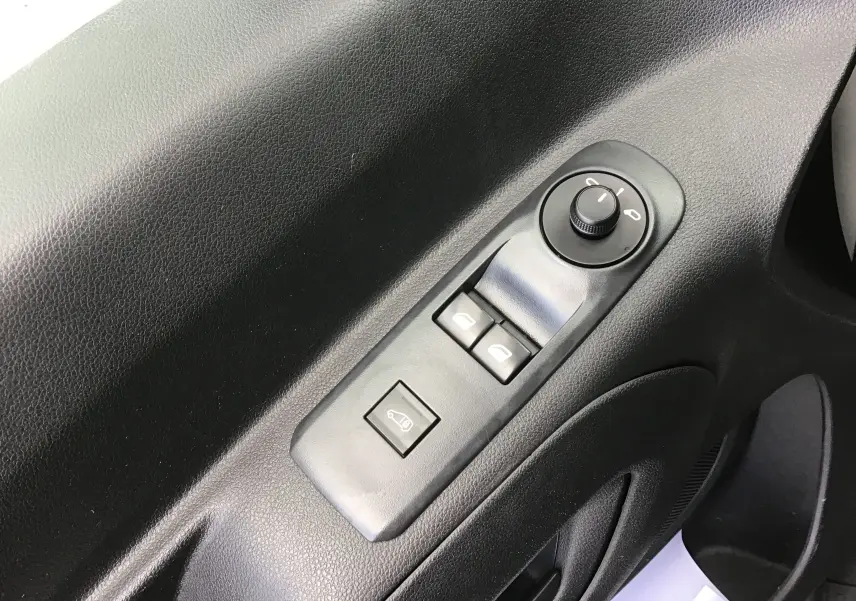 Vue rapprochée des commandes électriques de vitres et rétroviseurs sur la porte intérieure noire d’un Peugeot Partner blanc.