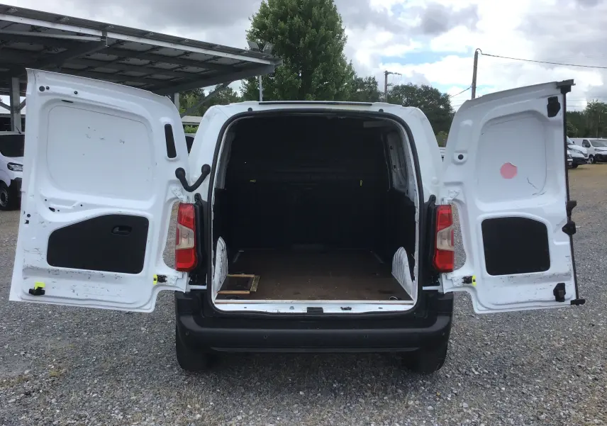 Vue arrière du Peugeot Partner blanc 2022 avec portes battantes ouvertes dévoilant l’espace de chargement vide.