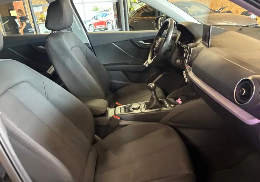 Intérieur noir de l'Audi Q2 30 1.6 TDI 2020 vu côté droit, mettant en valeur la boîte manuelle et le tableau de bord.