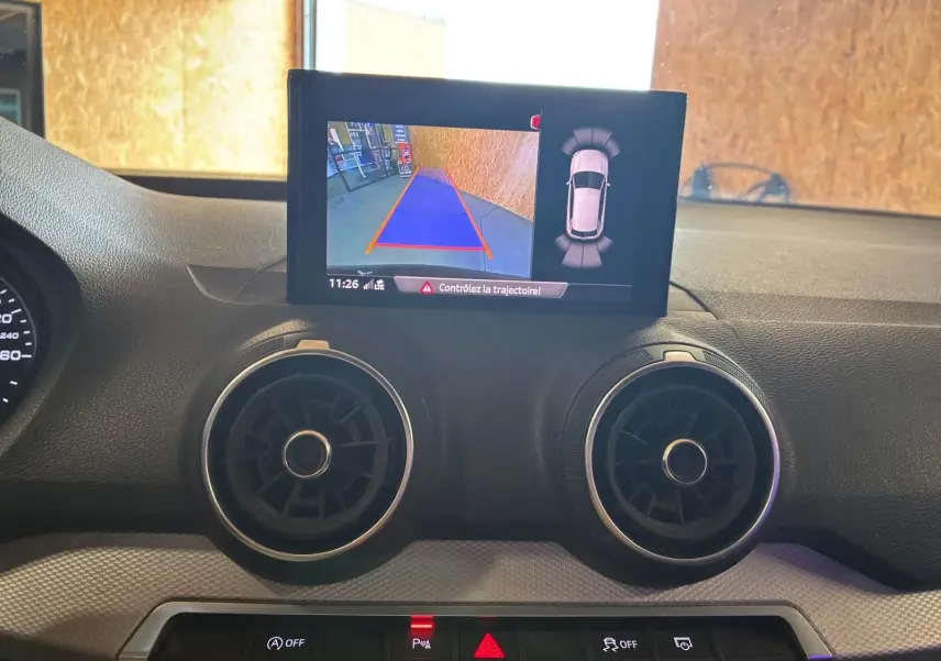 Vue intérieure du tableau de bord de l'Audi Q2 2020 noir, avec écran de caméra de recul et aérateurs ronds.