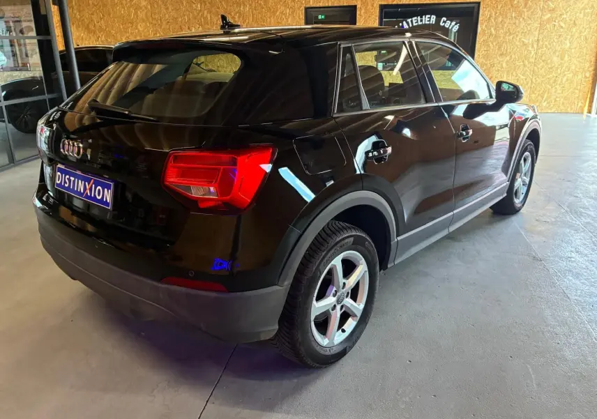 Audi Q2 noire vue 3/4 arrière droit, mettant en valeur ses feux arrière rouges et ses jantes alliage argentées.