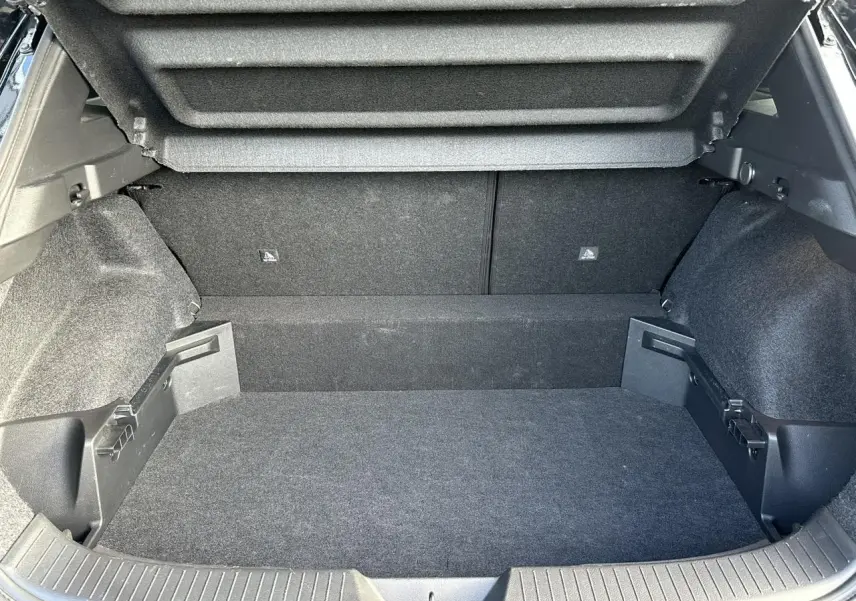 Coffre ouvert du Nissan Qashqai III noir nacré, montrant le plancher modulable et les côtés tapissés en tissu gris.