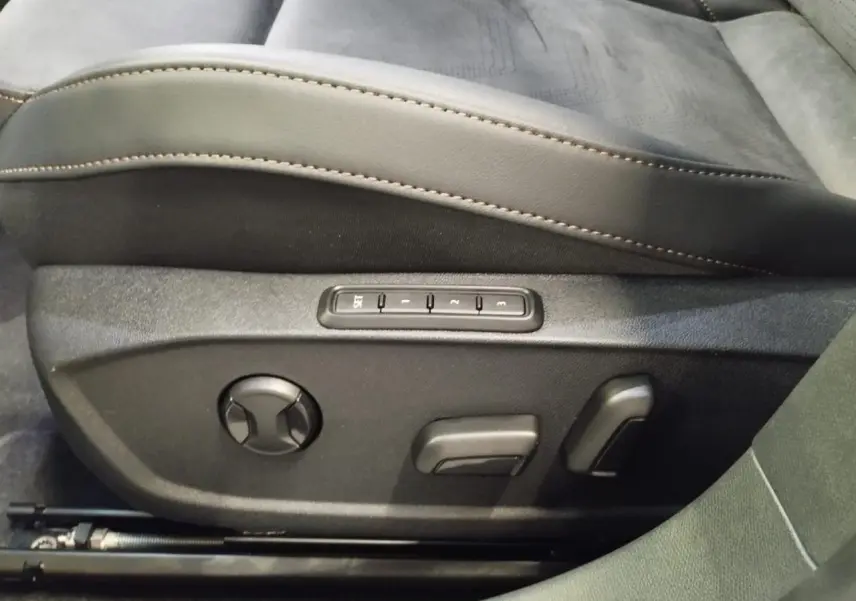 Gros plan sur les commandes électriques du siège conducteur en suédine noire avec surpiqûres cuivrées du CUPRA Formentor blanc.