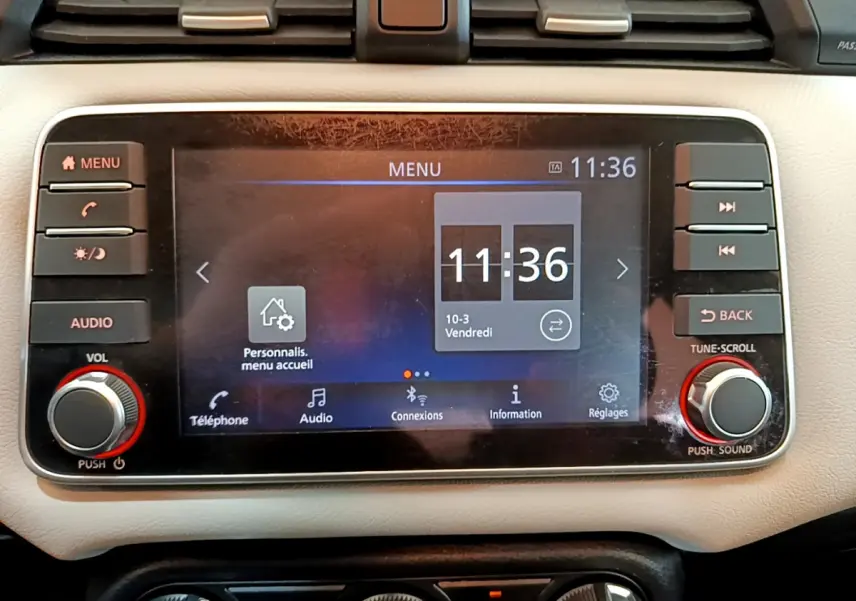 Écran tactile central du tableau de bord beige de la Nissan Micra IG-T 92 Acenta 2022 affichant l'heure et le menu principal.