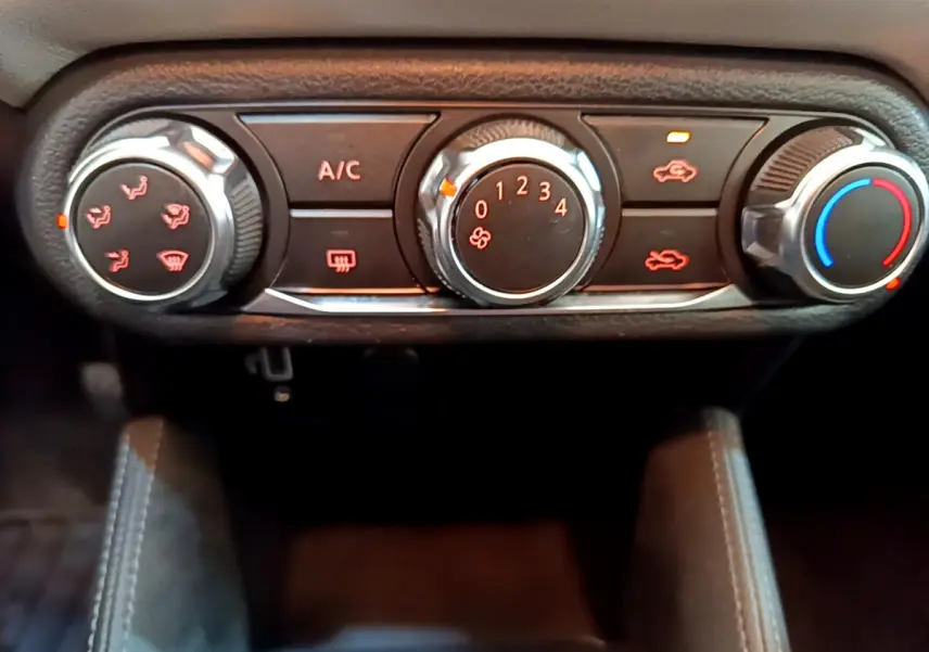 Gros plan sur les commandes de climatisation manuelle de la Nissan Micra IG-T 92 Acenta 2022, boutons noirs et chrome.