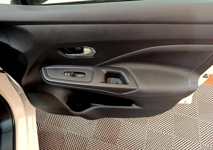 Vue rapprochée de la porte avant gauche noire de la Nissan Micra blanche 2022, avec commandes de vitres et poignée chrome.