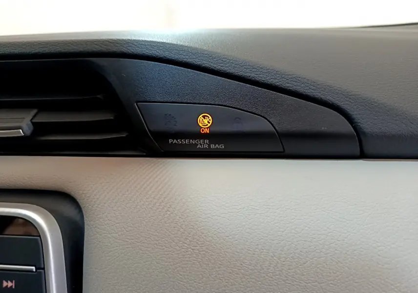 Gros plan sur le tableau de bord beige et noir de la Nissan Micra 2022, voyant airbag passager allumé en orange.