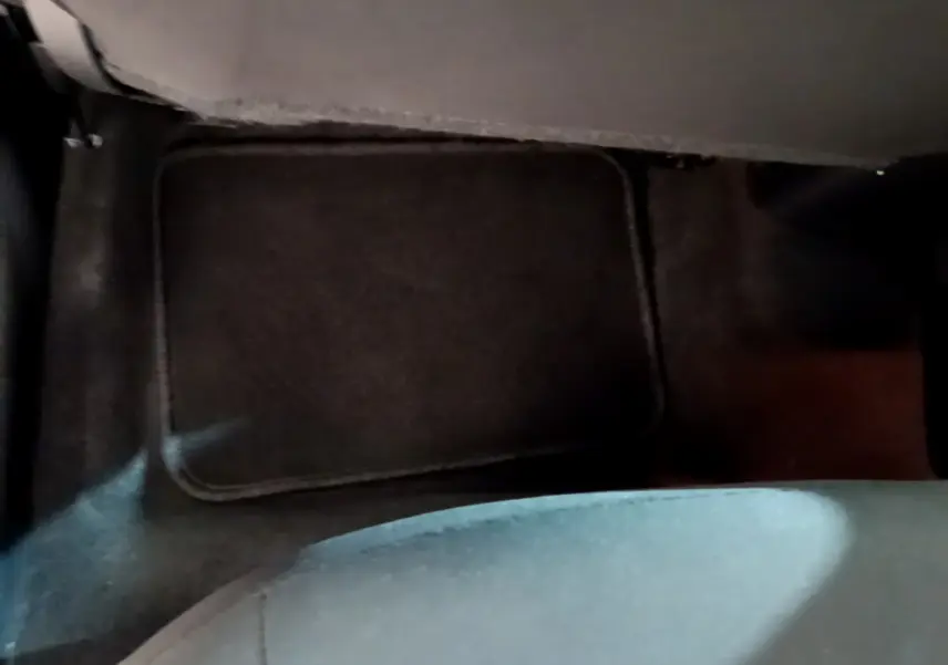 Vue rapprochée du tapis de sol noir au niveau du plancher arrière d'une Nissan Micra IG-T 92 Acenta blanche.