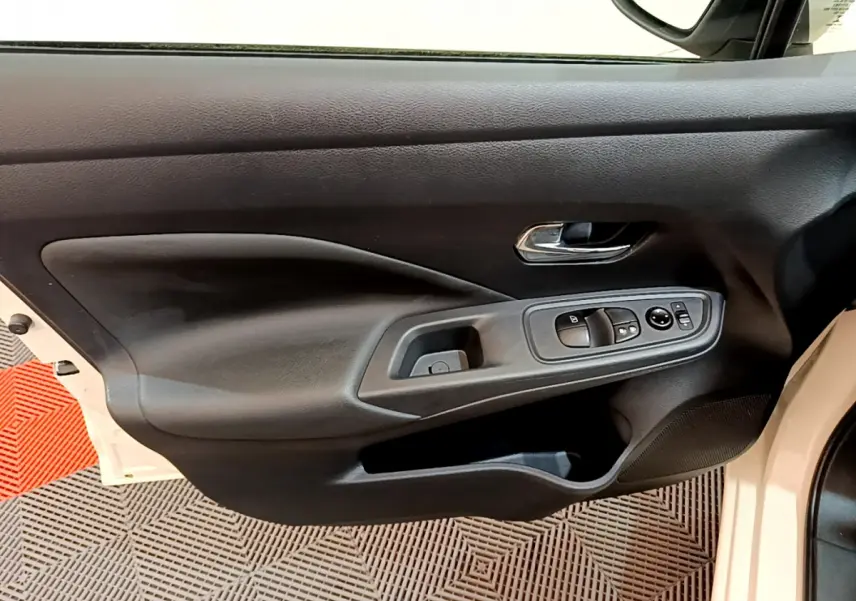 Vue intérieure côté gauche de la porte avant d'une Nissan Micra blanche 2022 avec commandes électriques et poignée chrome.