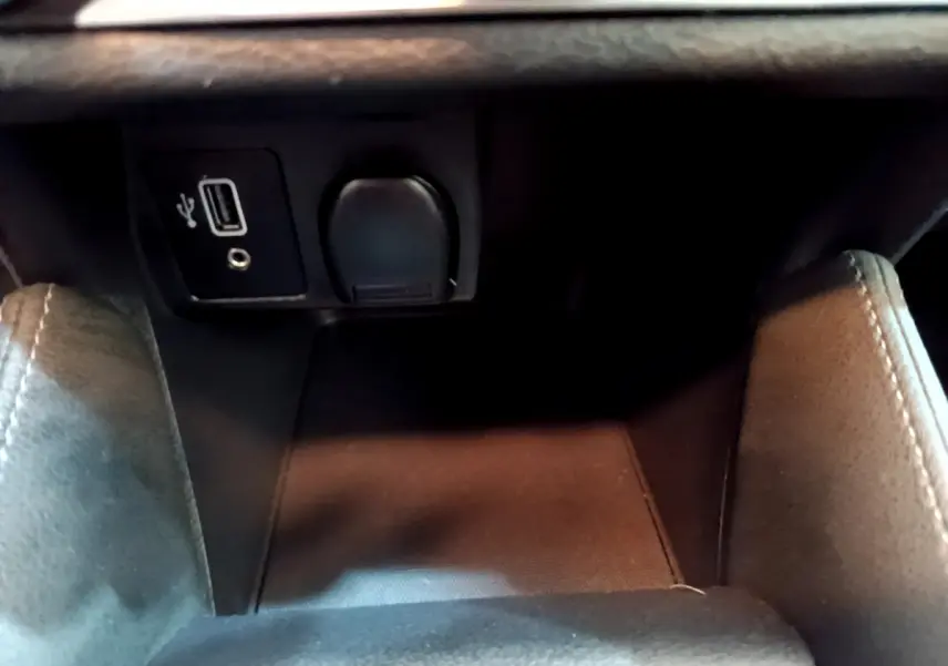 Prise USB et prise 12V noires dans le compartiment central avant de la Nissan Micra blanche IG-T 92 Acenta 2022.