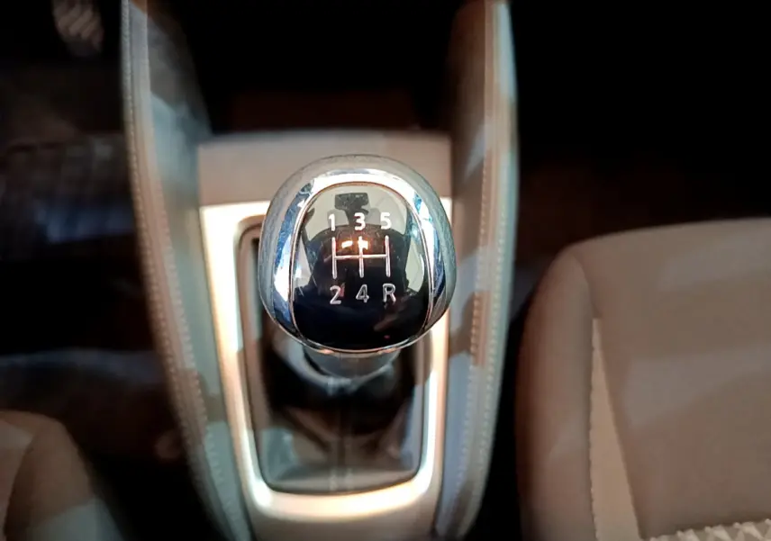 Le levier de vitesses manuel vu de dessus dans l'habitacle beige de la Nissan Micra IG-T 92 Acenta 2022.