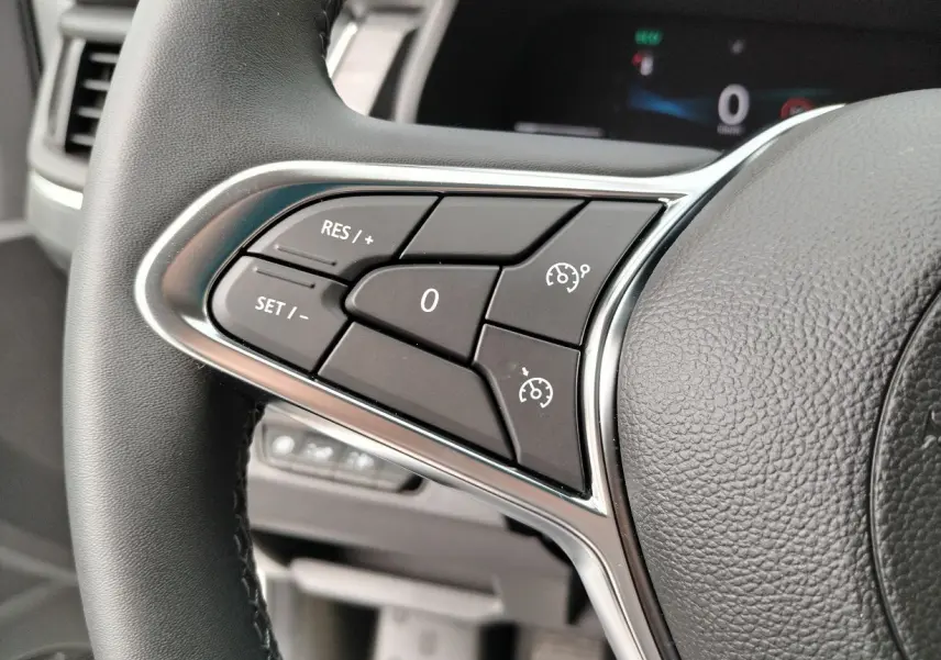 Gros plan sur les commandes de régulateur de vitesse au volant noir du Nissan Primastar 2025.