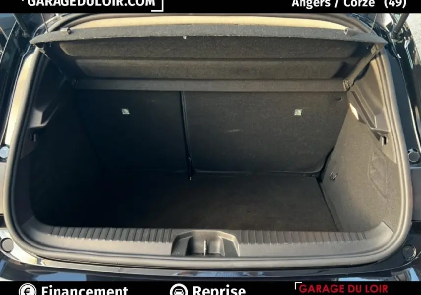 Coffre ouvert vu de l'arrière d'une Renault Clio noire 2025, intérieur spacieux et tapis noir visible.