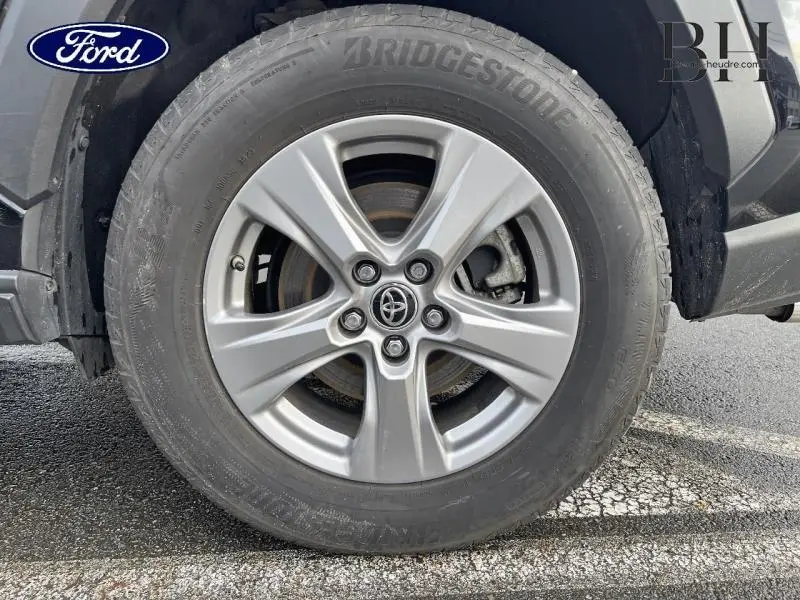 Gros plan sur la roue avant gauche avec jante alu argentée et pneu Bridgestone du Toyota RAV4 noir métallisé.