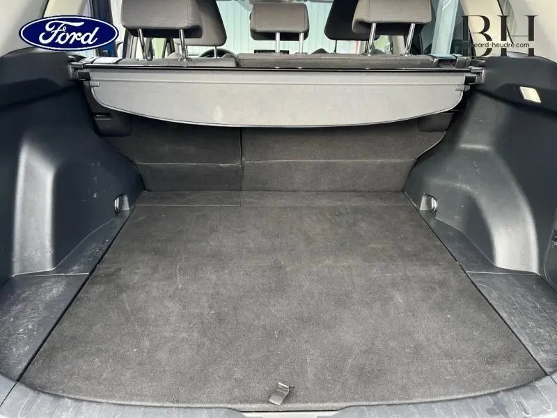Coffre ouvert vu de l'arrière d'un Toyota RAV4 noir métallisé avec cache-bagages et banquette arrière rabattable.