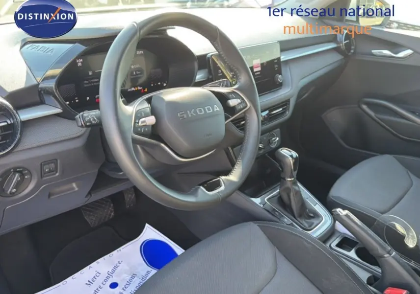 Vue intérieure de face du poste de conduite gris noir de la Skoda Fabia 2025 avec volant multifonction et écran tactile central.