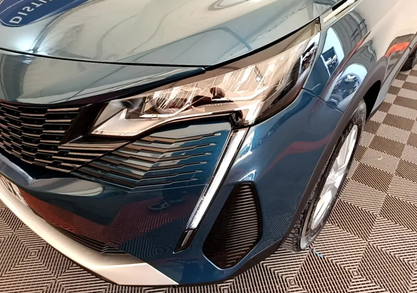 Gros plan sur l’avant droit bleu du Peugeot 3008 2022, mettant en valeur le phare LED et la calandre distinctive.