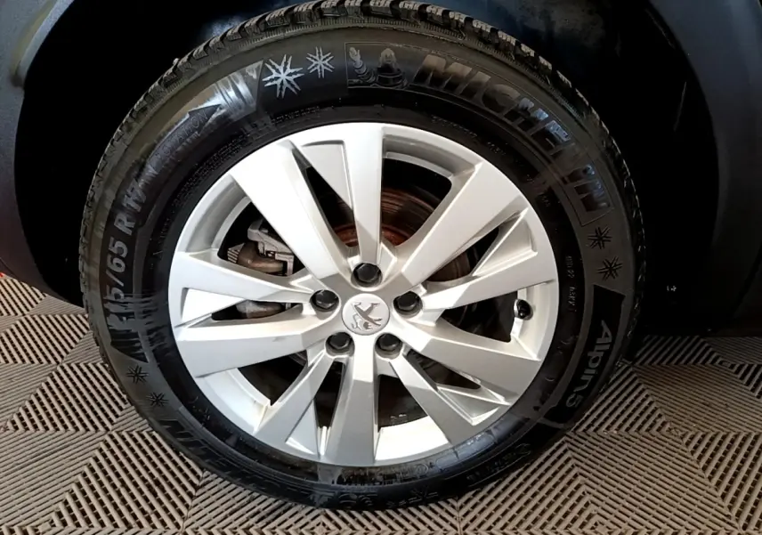 Gros plan sur la roue avant droite du Peugeot 3008 bleu, avec jante alliage argentée et pneu Michelin hiver.