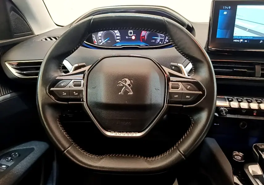 Vue intérieure centrée sur le volant cuir noir de la Peugeot 3008 avec tableau de bord digital et écran tactile.