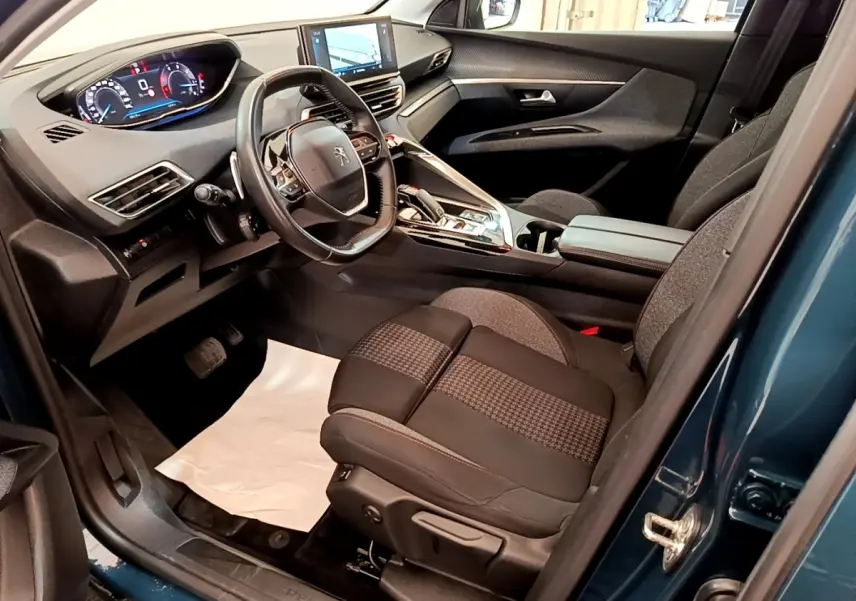 Vue intérieure côté conducteur du Peugeot 3008 bleu 2022, montrant le tableau de bord digital et le volant cuir multifonctions.